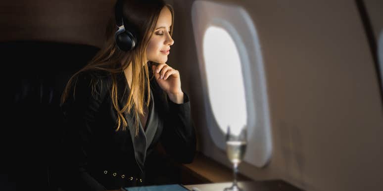woman relaxes in business class flight with glass of champagne