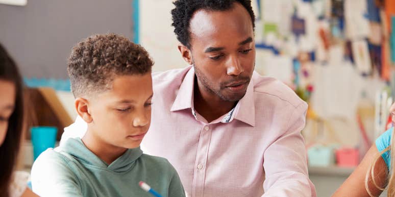 Middle school teacher helping student in class