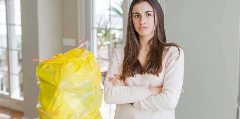 Wife angry near a trash bag with cheating husband's clothing. 