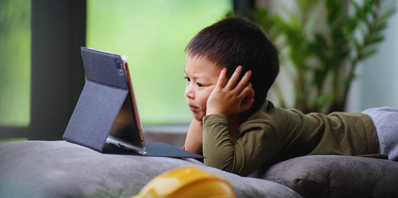 young child watching tablet screen sitting on couch at home