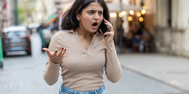 angry woman walking down the street talking on the phone