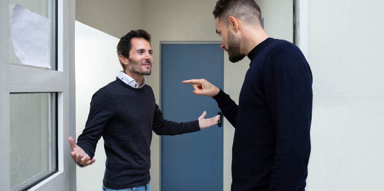 two men arguing in front of a door