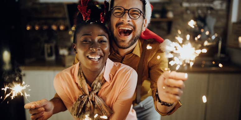 cheerful couple having fun with sparklers on New Year's eve at home.