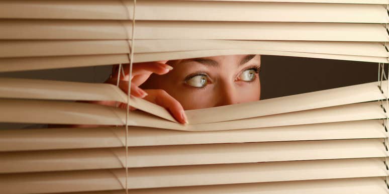 woman looking out the blinds of haunted house at rug buried in backyard