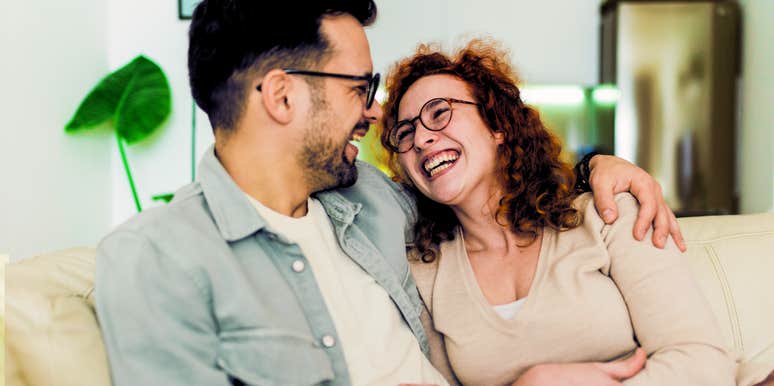 Woman showering partner in words of positivity as they laugh together on couch. 