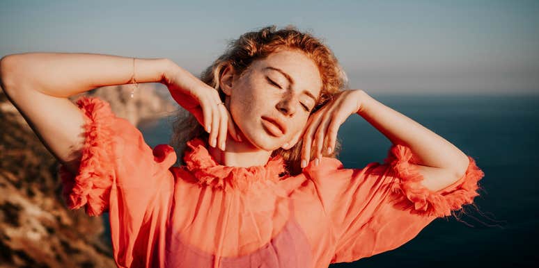 Close up shot of woman with curly red hair and freckles looking off camera