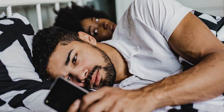 Man texting another woman while partner is in bed with him.