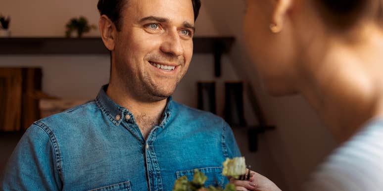 Man lovingly handing woman a plate of food.