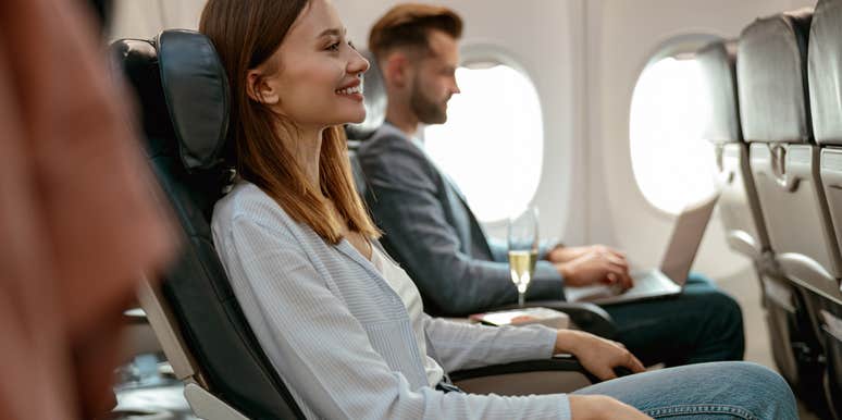 Cheerful woman sitting in passenger chair in airplane