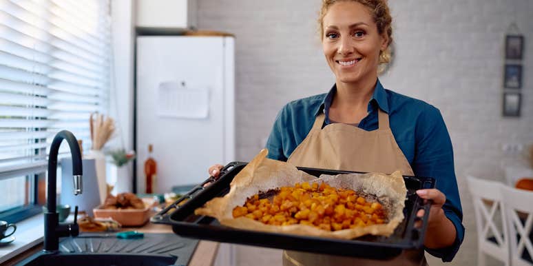 woman cooking Thanksgiving dinner in the kitchen holding up tray of food