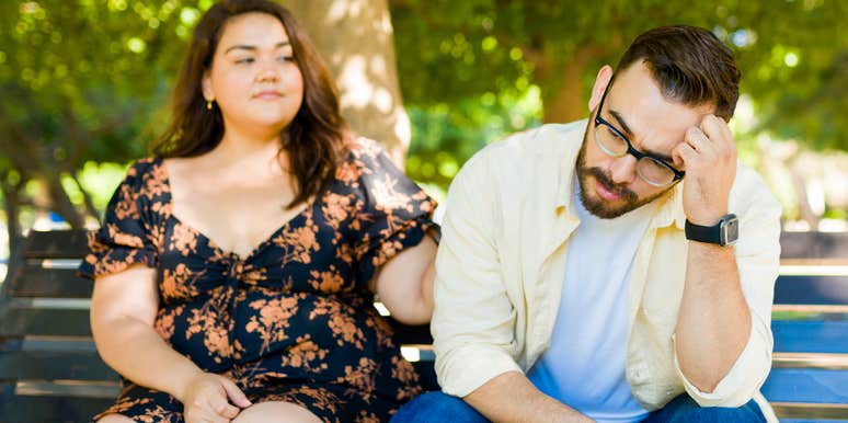 Couple lazily sitting on a bench.