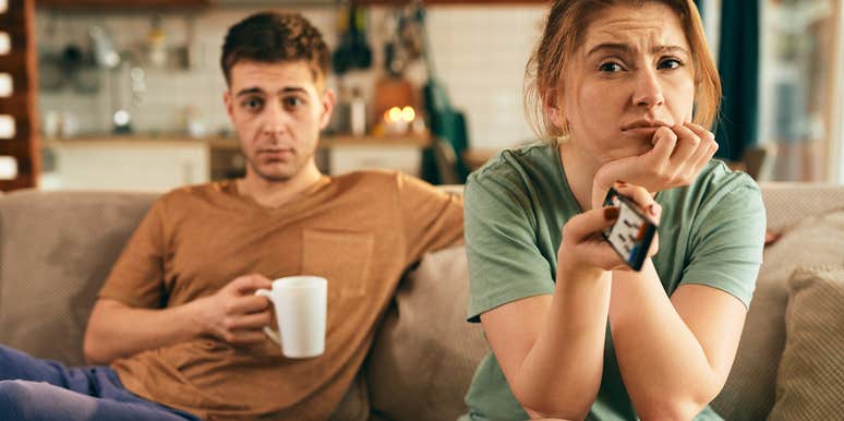 Married couple looking bored and sitting on the couch together. 