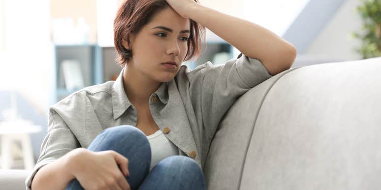 Depressed young woman sitting on sofa at home