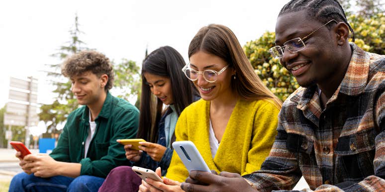 Group of teenage college friend students ignoring each other looking at mobile phone.