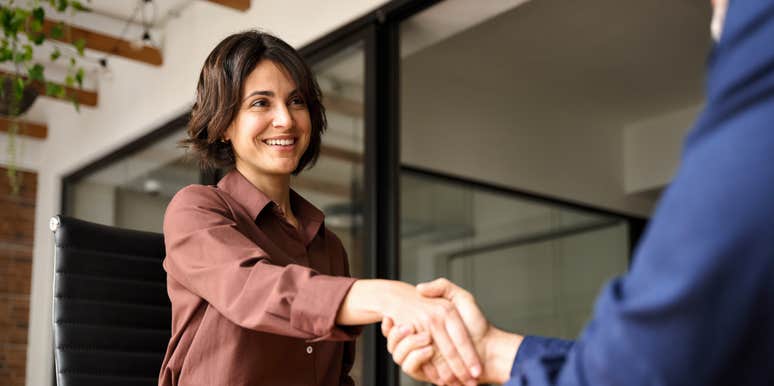 Happy young business woman bank manager handshaking client at meeting