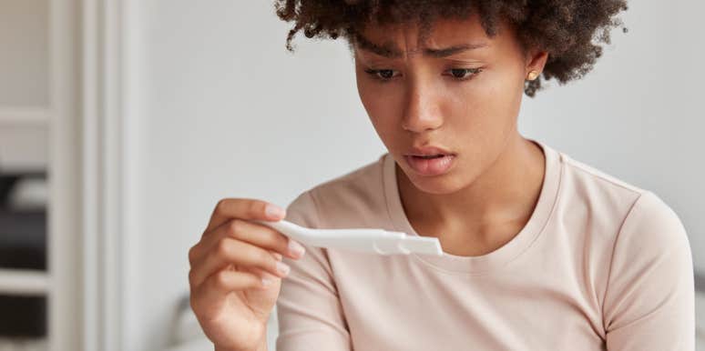 Concerned mom-to-be looking at positive pregnancy test