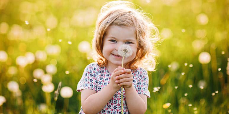 happy little girl holding a dandelion