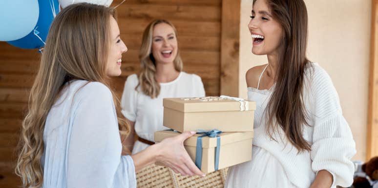 woman handing baby shower gifts to pregnant woman