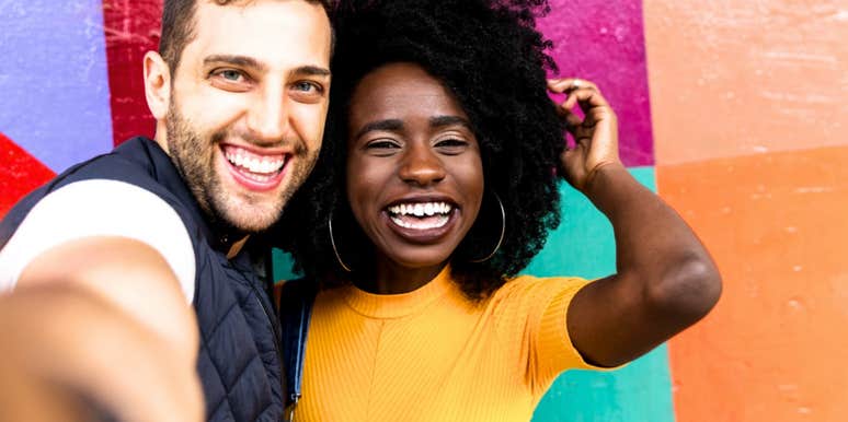 Happy couple in bright colors smiles at the camera 