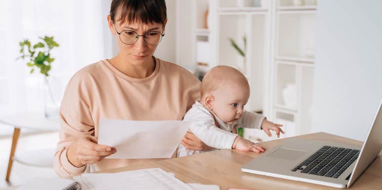 woman staring at bill in surprise while holding her baby