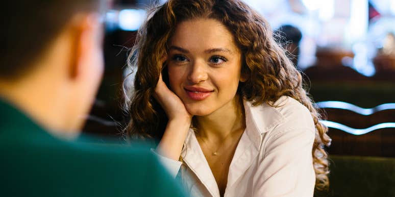 Smiling young woman talking to male friend at romantic date in cafe