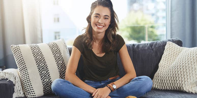 Millennial woman sitting on a couch smiling