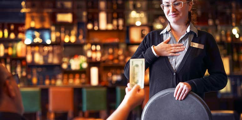 man handing tip to server in restaurant