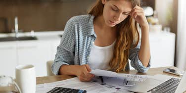 young woman holding papers in her hands calculating family budget