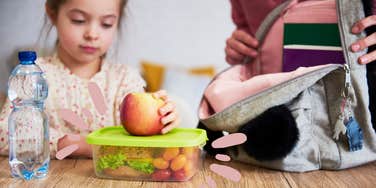 mom helps child pack lunch for school