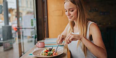  smiling woman eating salad at restaurant