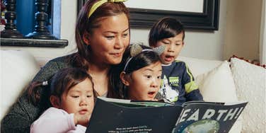 single mom reads a book to her three kids 