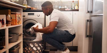 man putting laundry in washing machine