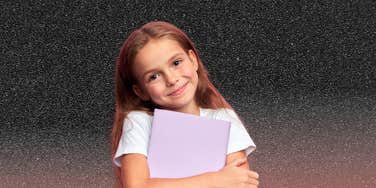 little girl holding a diary looking silently at the camera