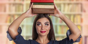 Woman who is smart holds books above heads and knows she excels in certain areas of life.