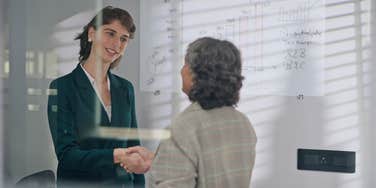 female business partners shake hands during meeting in workplace