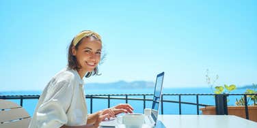 woman on laptop by the beach 