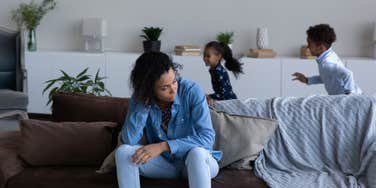 mother feeling tired of noisy little children playing around her