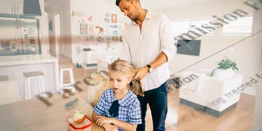 Man getting child ready for school, signing permission slip