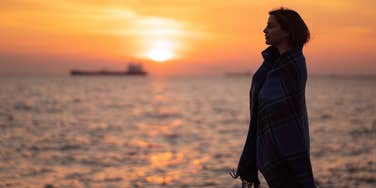 pensive introspective woman reflects while watching sunset at the beach