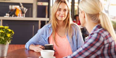 two blonde friends talking over coffee at cafe 