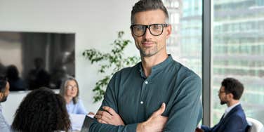 CEO standing in meeting room with arms crossed 