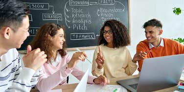 gen z employees smiling while sitting around table at work