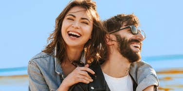 couple in a healthy relationship laughing at the beach