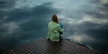 Woman sits alone in front of water