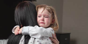 little girl crying hugging her mother