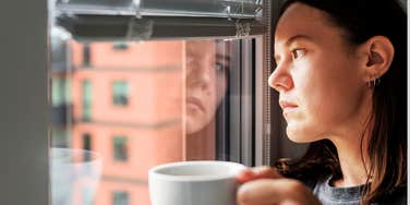 Woman looking out window of home