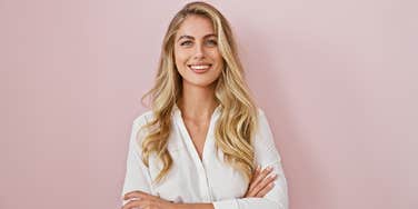 pretty blonde woman standing against pink background