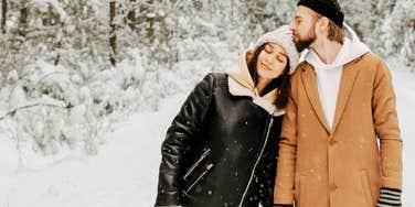 Couple cuddling as they walk in the winter snow.