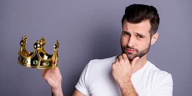 man holding a crown thinking about whether or not to wear it