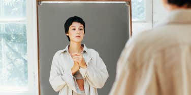 Woman looking at herself in mirror.